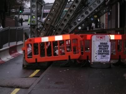 Newspaper headlines on sign by roadworks: 'ROAD REPAIRS MISERY FOR XMAS SHOPPERS'